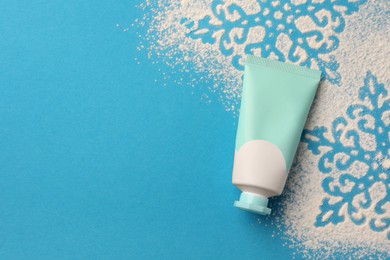Tube of hand cream and snowflakes on light blue background, top view with space for text. Winter skin care