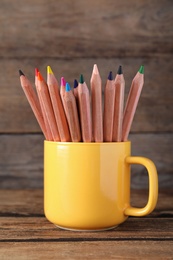 Colorful pencils in cup on wooden table