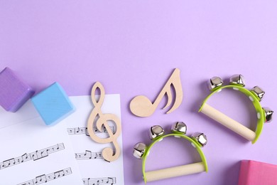 Tools for creating baby songs. Flat lay composition with wooden notes and tambourines for kids on violet background