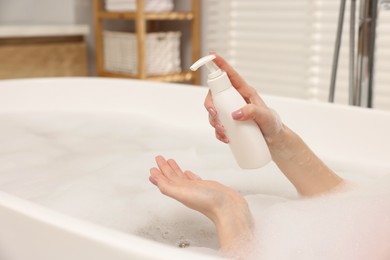 Photo of Woman applying shower gel onto hand in bath indoors, closeup. Space for text
