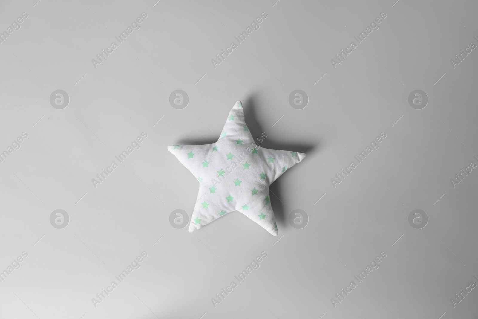 Photo of Soft pillow in shape of star on light background