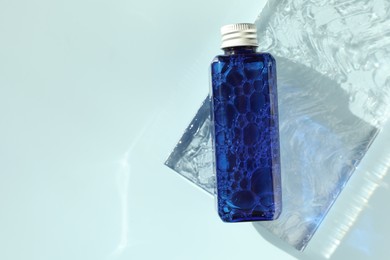 Photo of Bottle of cosmetic product on light blue background, top view. Space for text