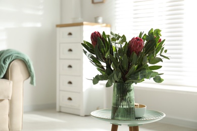 Vase with bouquet of beautiful Protea flowers on table at home