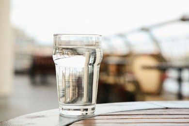 Photo of Glass of fresh water on table outdoors, closeup. Space for text