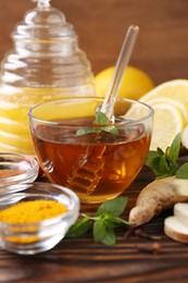 Photo of Tea with honey and ingredients on wooden table