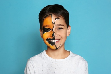 Cute little boy with face painting on blue background