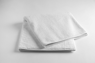 Photo of Folded soft terry towel on light background