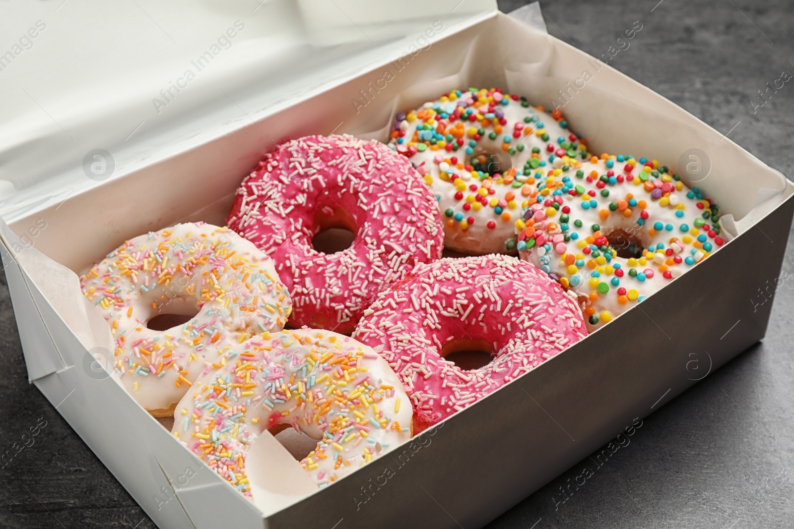 Photo of Delicious glazed donuts on grey table, closeup