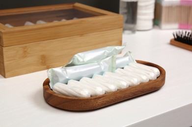 Photo of Wooden tray with many tampons on white table. Menstrual hygienic product