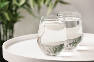 Photo of Glasses with water on table against blurred background. Space for text