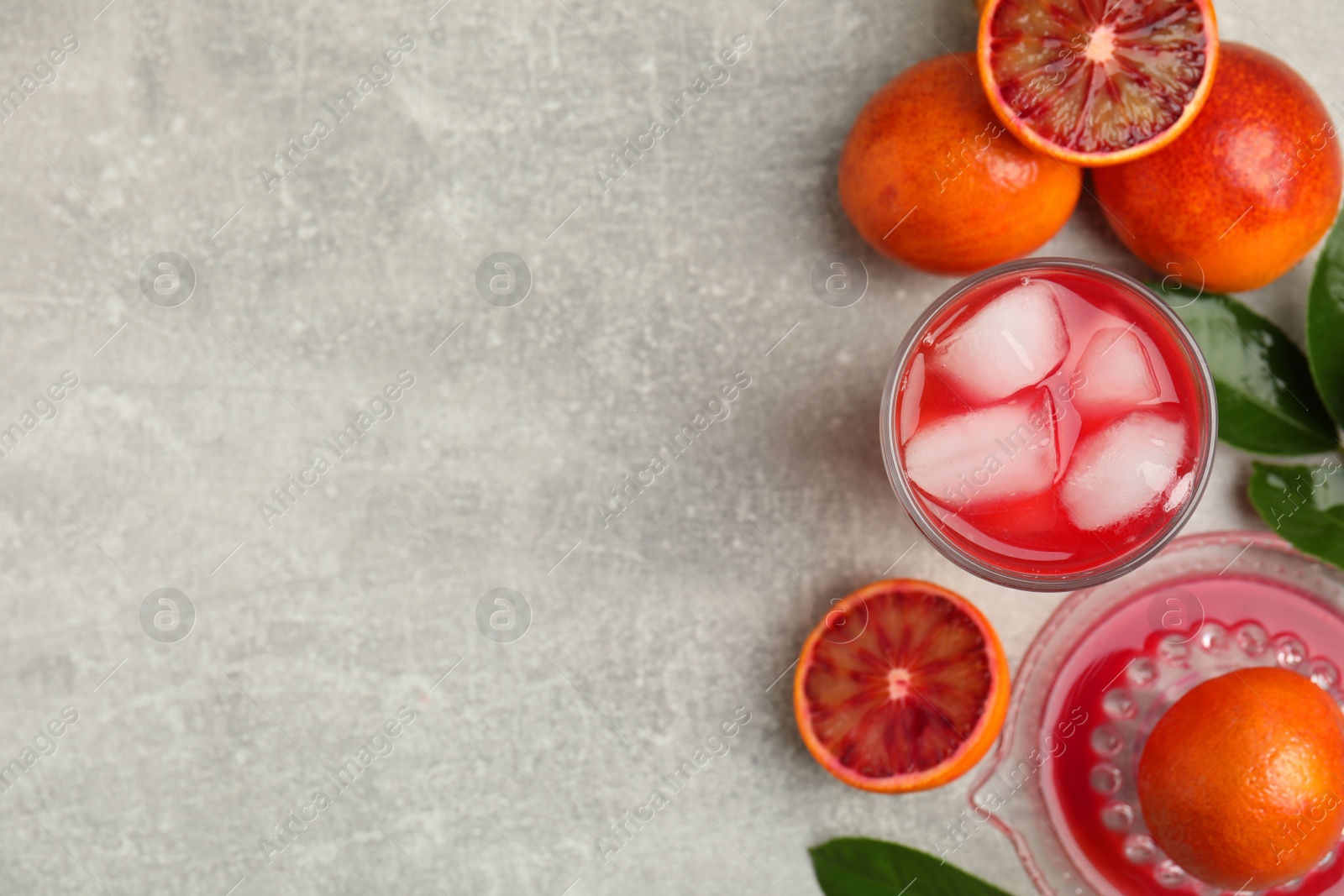 Photo of Tasty sicilian orange juice with ice cubes and fruits on light grey table, flat lay. Space for text