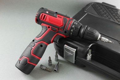 Photo of Electric screwdriver, drill bits and case on grey background