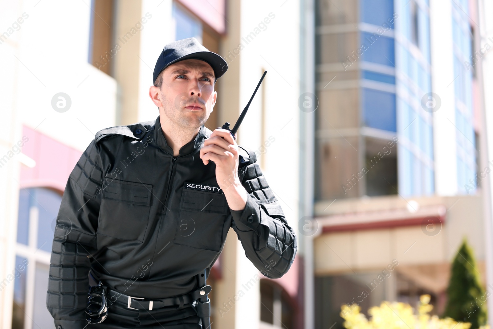 Photo of Male security guard using portable radio transmitter outdoors