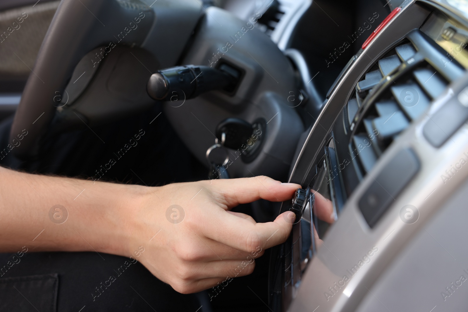 Photo of Listening to radio while driving. Man turning volume button on vehicle audio in car, closeup