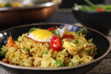 Tasty rice with meat, egg and vegetables in bowl on table, closeup