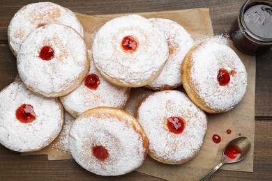 Many delicious donuts with jelly and powdered sugar on wooden table, flat lay
