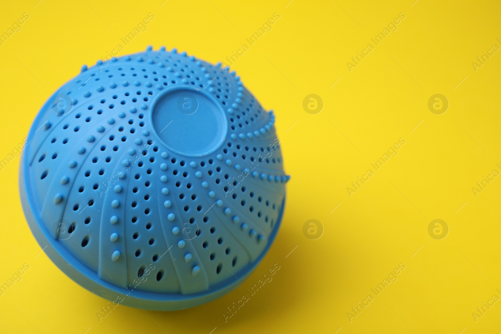 Photo of Laundry dryer ball on yellow background, space for text