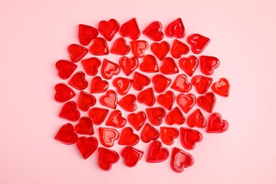 Photo of Sweet heart shaped jelly candies on pink background, flat lay
