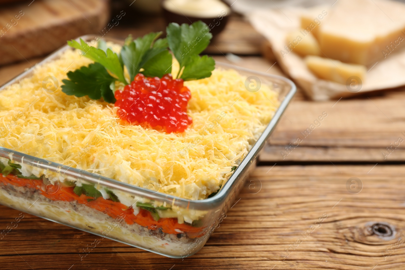 Photo of Traditional russian salad Mimosa served on wooden table, closeup.