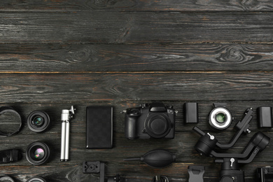 Flat lay composition with camera and video production equipment on black wooden table. Space for text