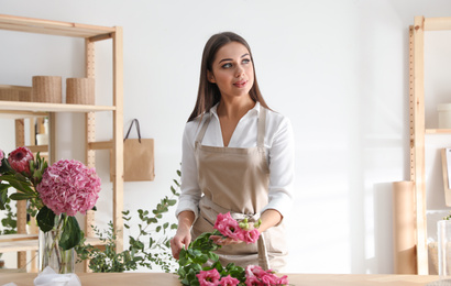 Florist making beautiful bouquet at table in workshop