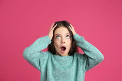 Portrait of cute little girl on pink background