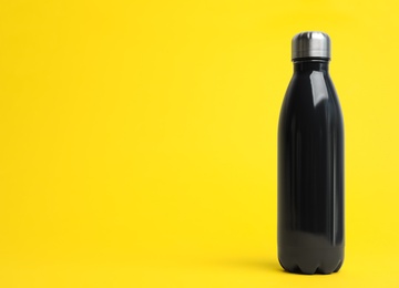 Photo of Stylish thermo bottle on yellow background, space for text