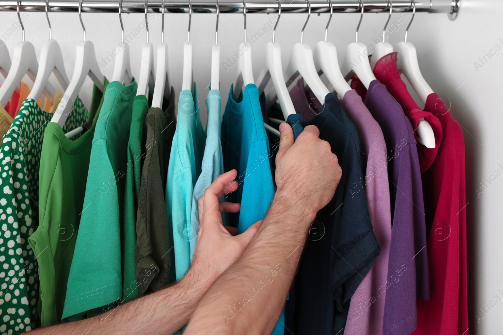 Photo of Man choosing clothes from rack in wardrobe, closeup