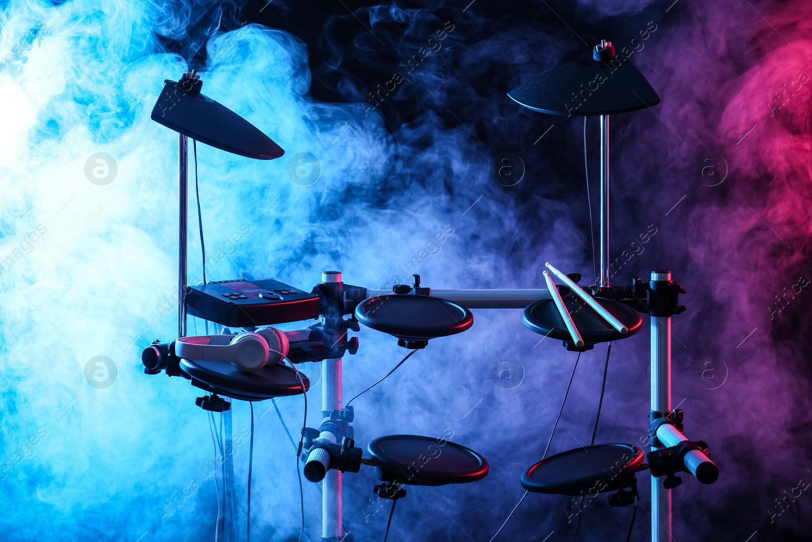 Photo of Modern electronic drum kit and smoke on dark background, color toned. Musical instrument