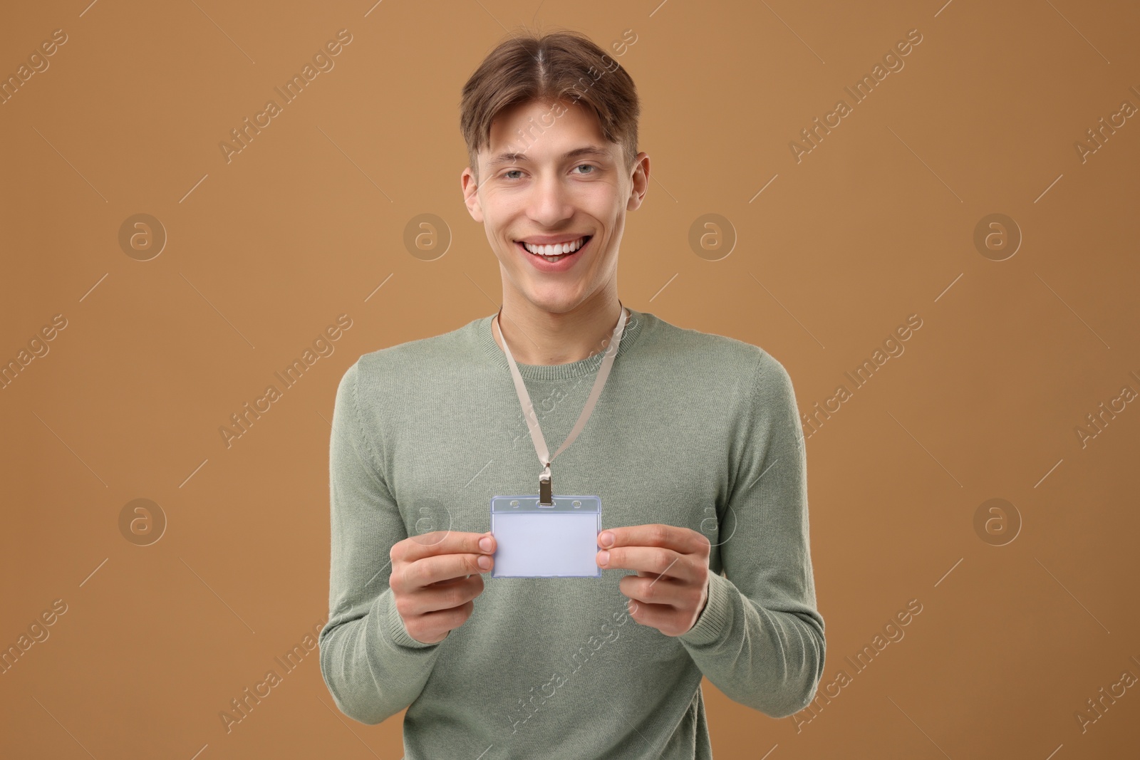 Photo of Happy man with blank badge on light brown background