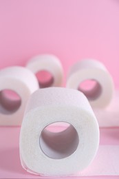 Photo of Soft toilet paper rolls on pink background, closeup