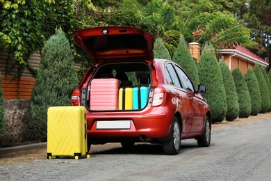 Photo of Open car trunk loaded with suitcases outdoors