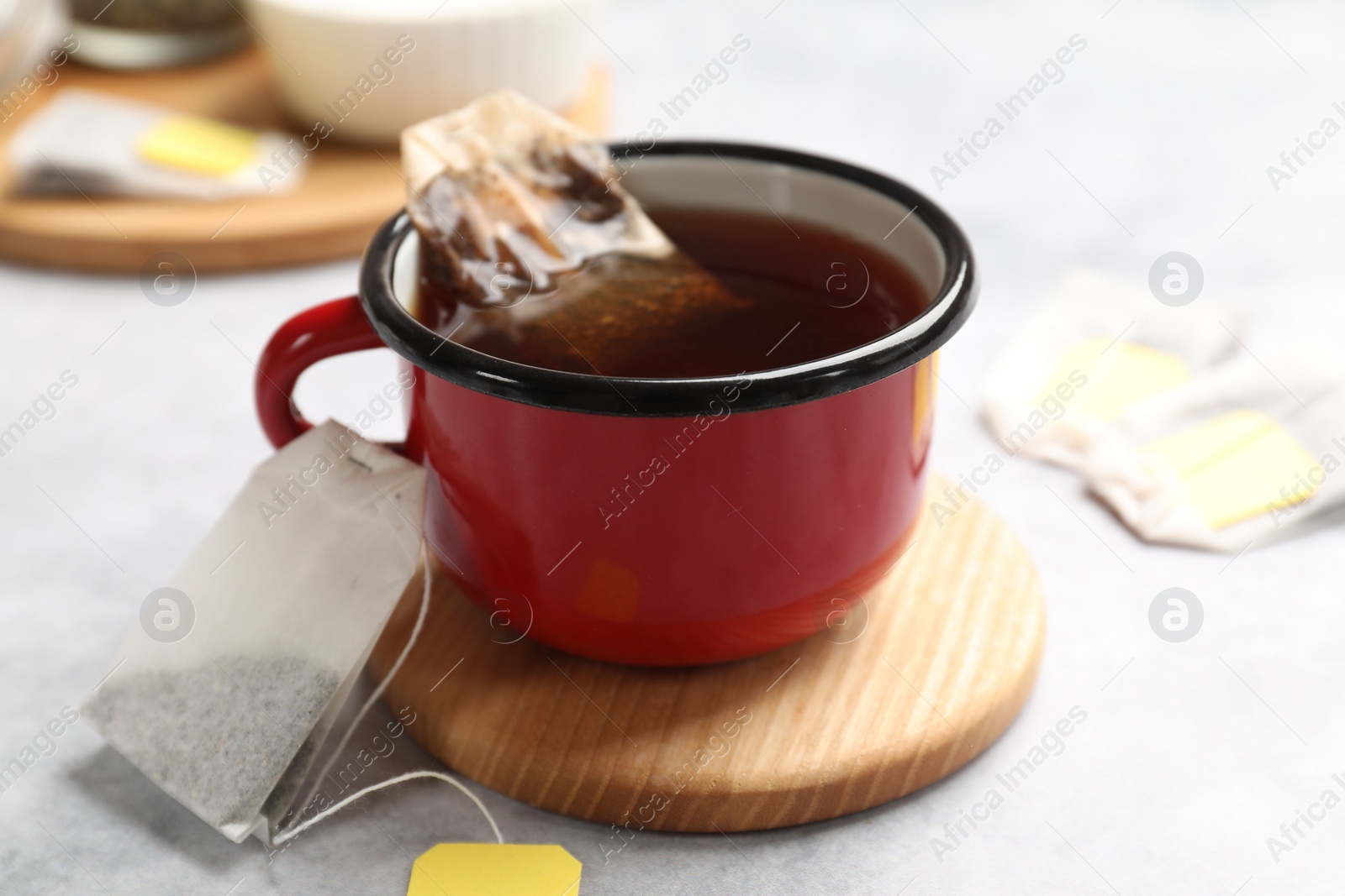 Photo of Tea bags and cup of hot beverage on light table, closeup