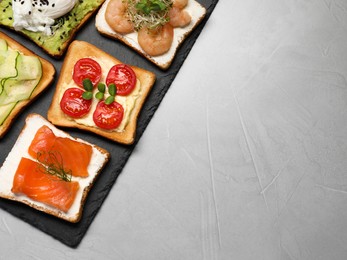 Different delicious toasts on light grey table, flat lay. Space for text
