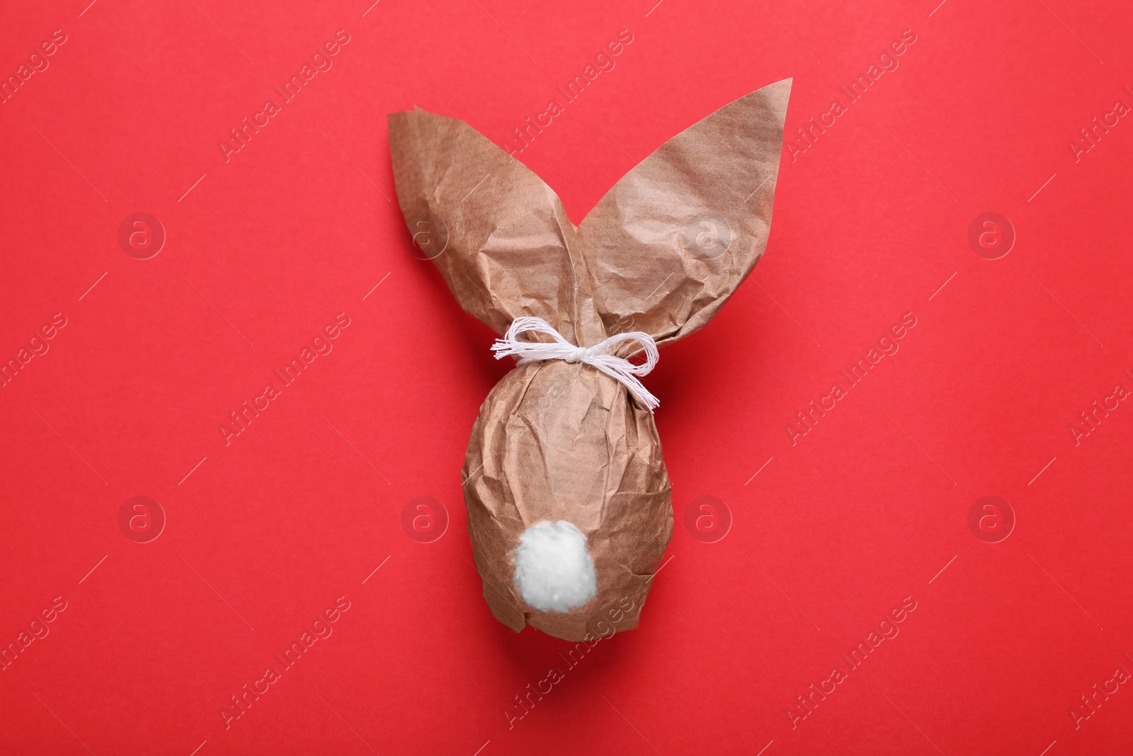 Photo of Easter bunny made of kraft paper on red background, top view