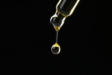 Photo of Dripping tincture from pipette on black background, closeup. Space for text