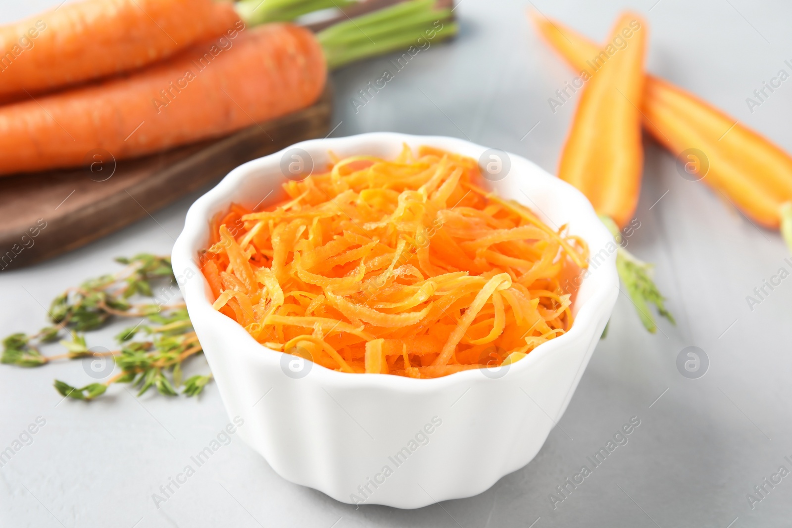 Photo of Bowl with grated ripe carrot on table