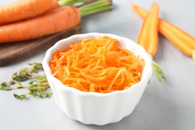 Photo of Bowl with grated ripe carrot on table