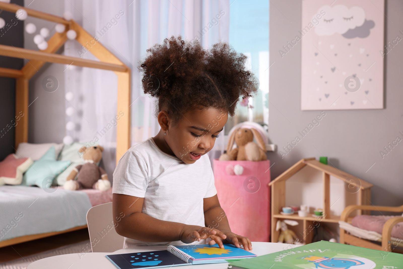 Photo of African American girl reading book at home