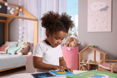 Photo of African American girl reading book at home