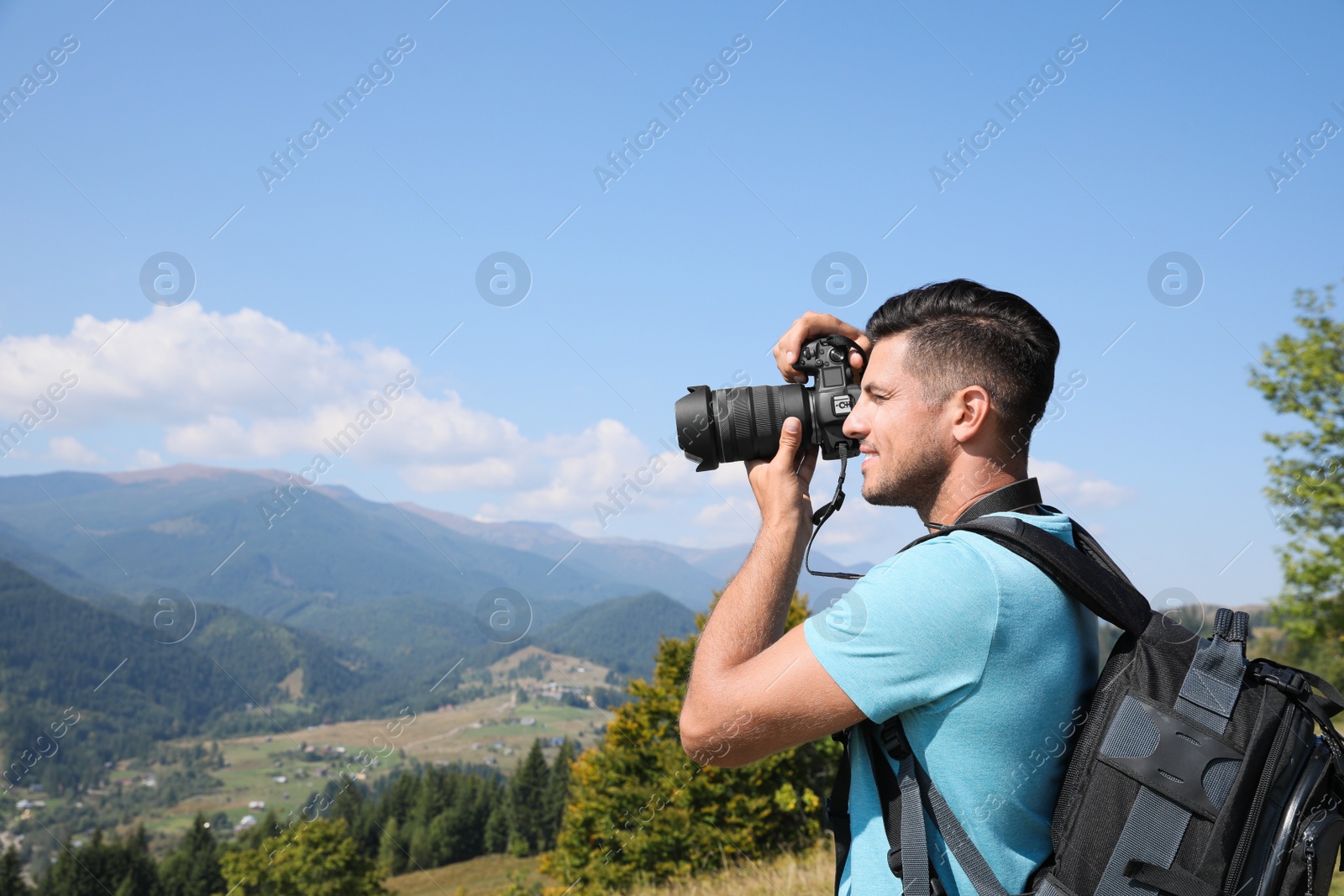 Photo of Professional photographer taking picture with modern camera in mountains. Space for text