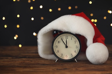 Vintage alarm clock with decor on wooden table against blurred Christmas lights. New Year countdown