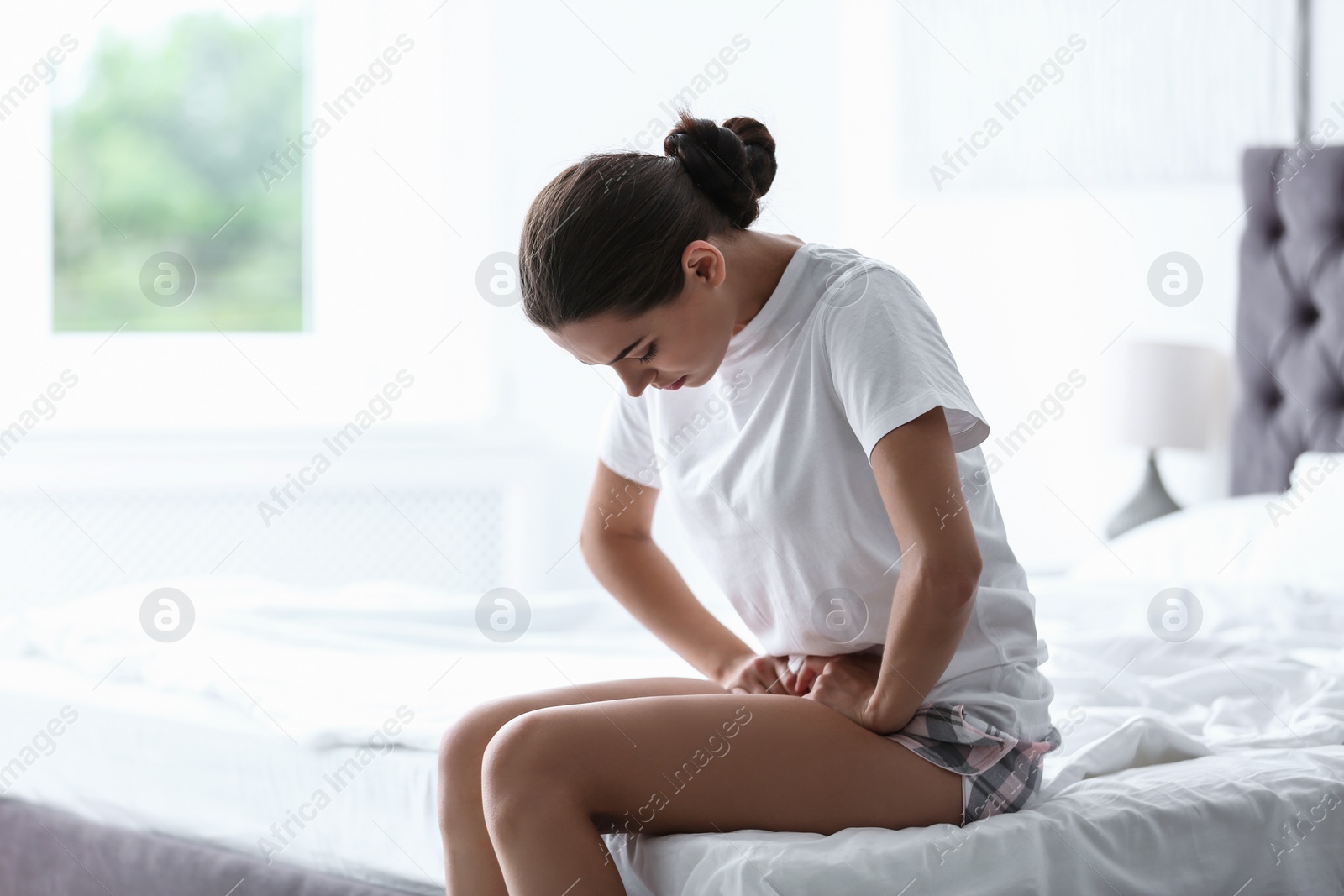 Photo of Young woman suffering from menstrual cramps at home. Gynecology