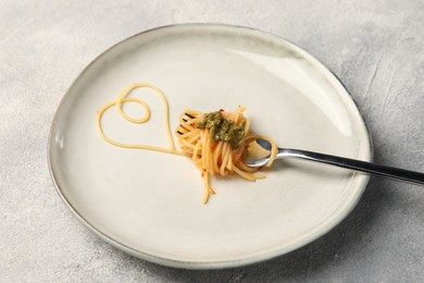 Photo of Heart made with spaghetti and fork on grey table