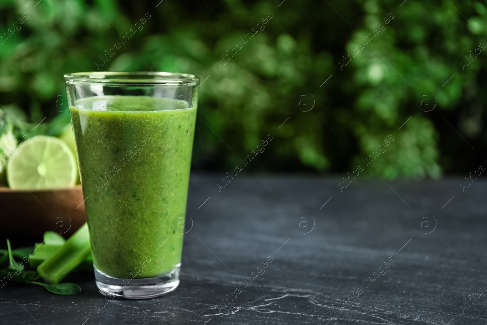 Photo of Delicious fresh green juice on black table, space for text