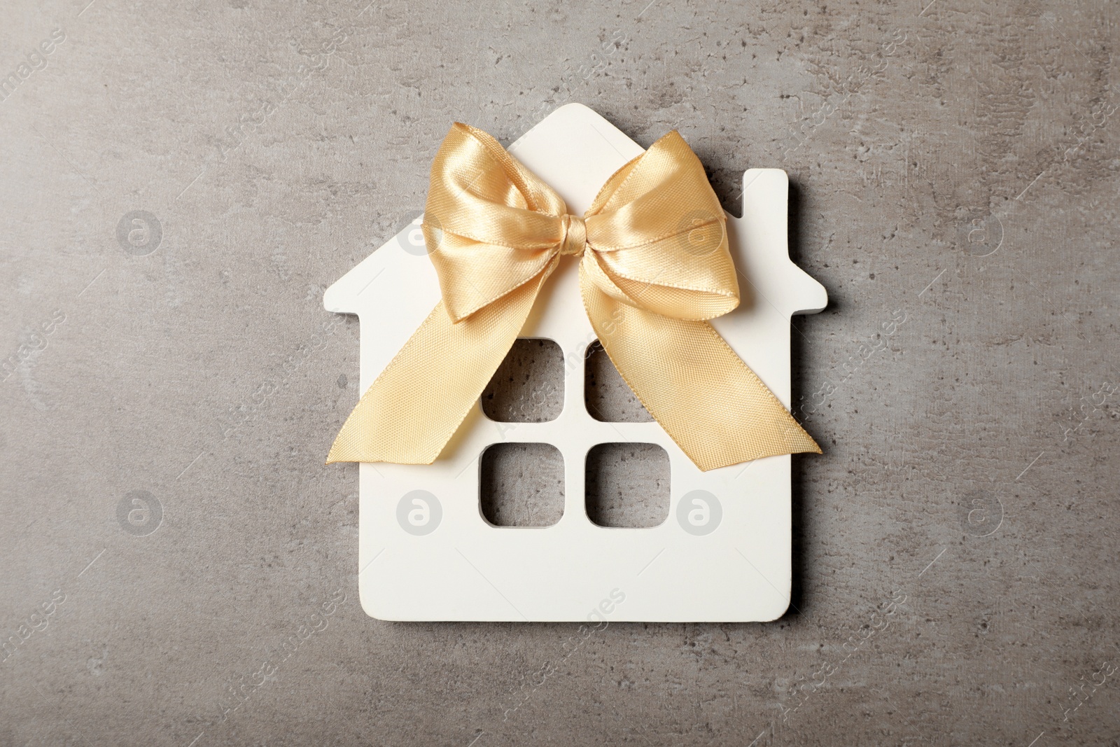 Photo of Wooden house model with bow on grey table, top view. Housewarming party