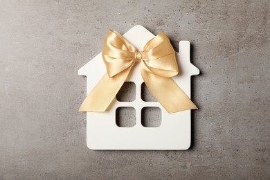 Wooden house model with bow on grey table, top view. Housewarming party