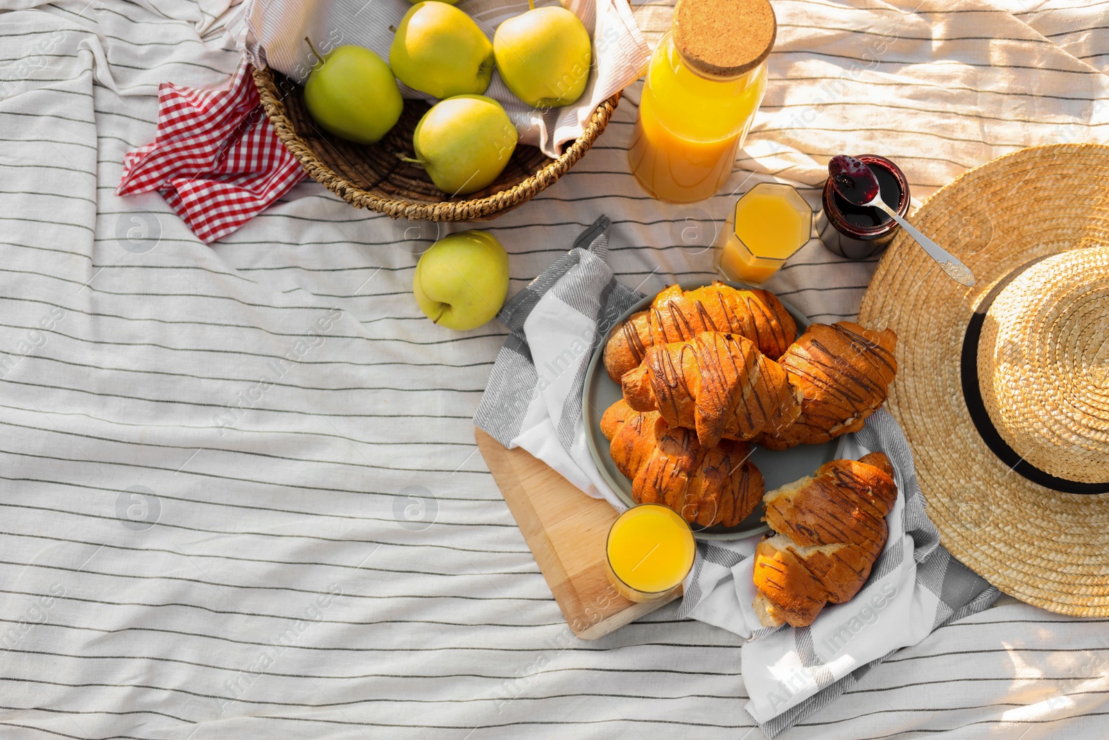 Photo of Delicious food and juice on striped blanket outdoors, flat lay. Picnic season