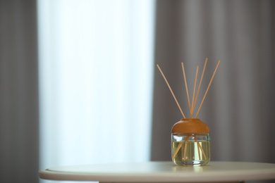 Aromatic reed air freshener on table indoors. Space for text