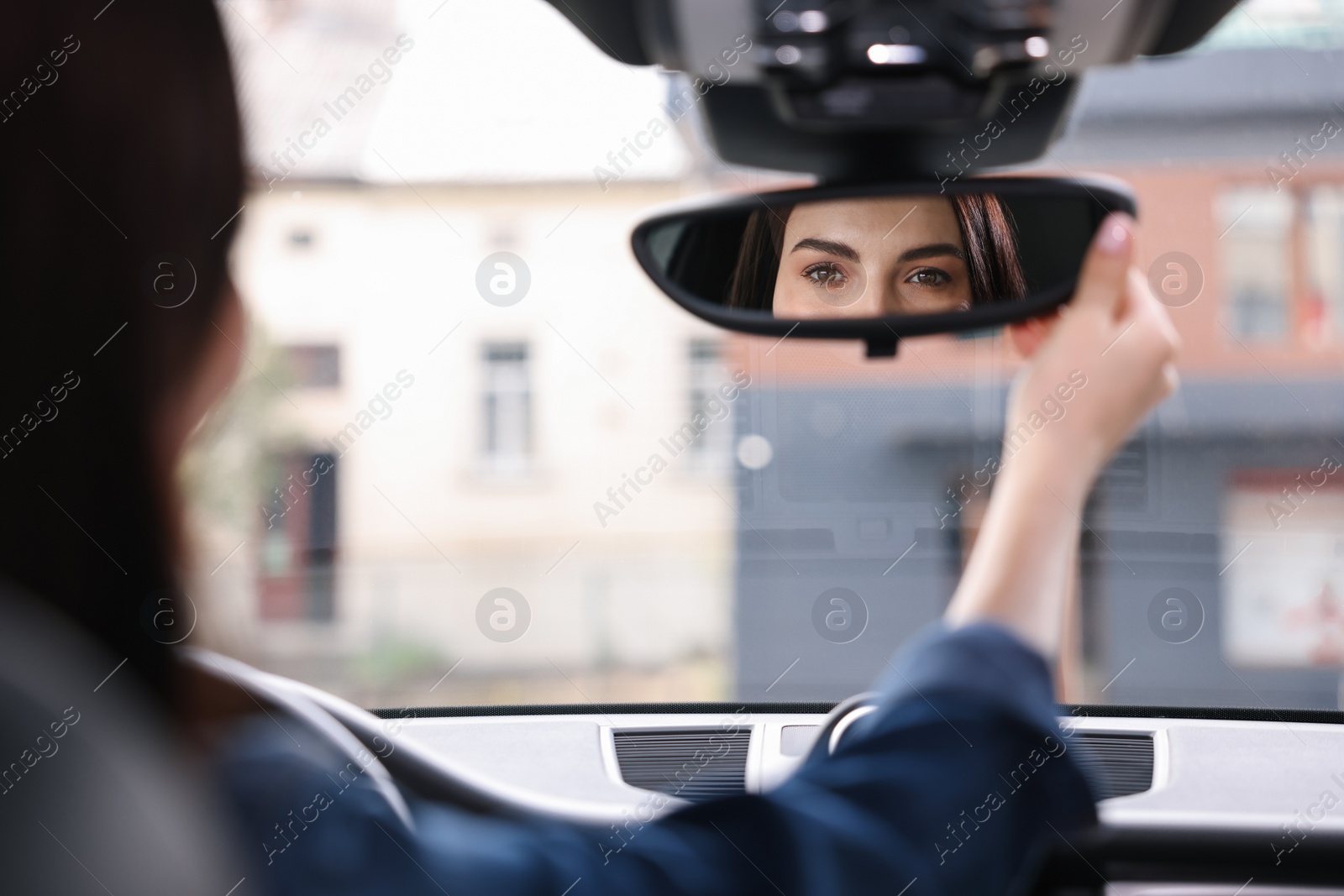 Photo of Woman adjusting rear view mirror inside her car, closeup